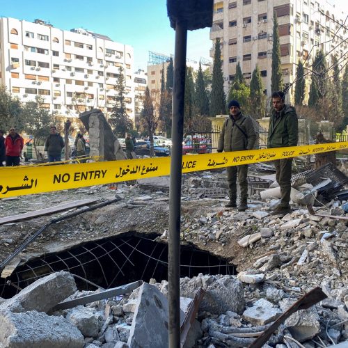 Police officers stand on the rubble of a damaged building at the site of a rocket attack, in central Damascus' Kafr Sousa neighborhood, Syria, February 19, 2023. REUTERS/Firas Makdessi